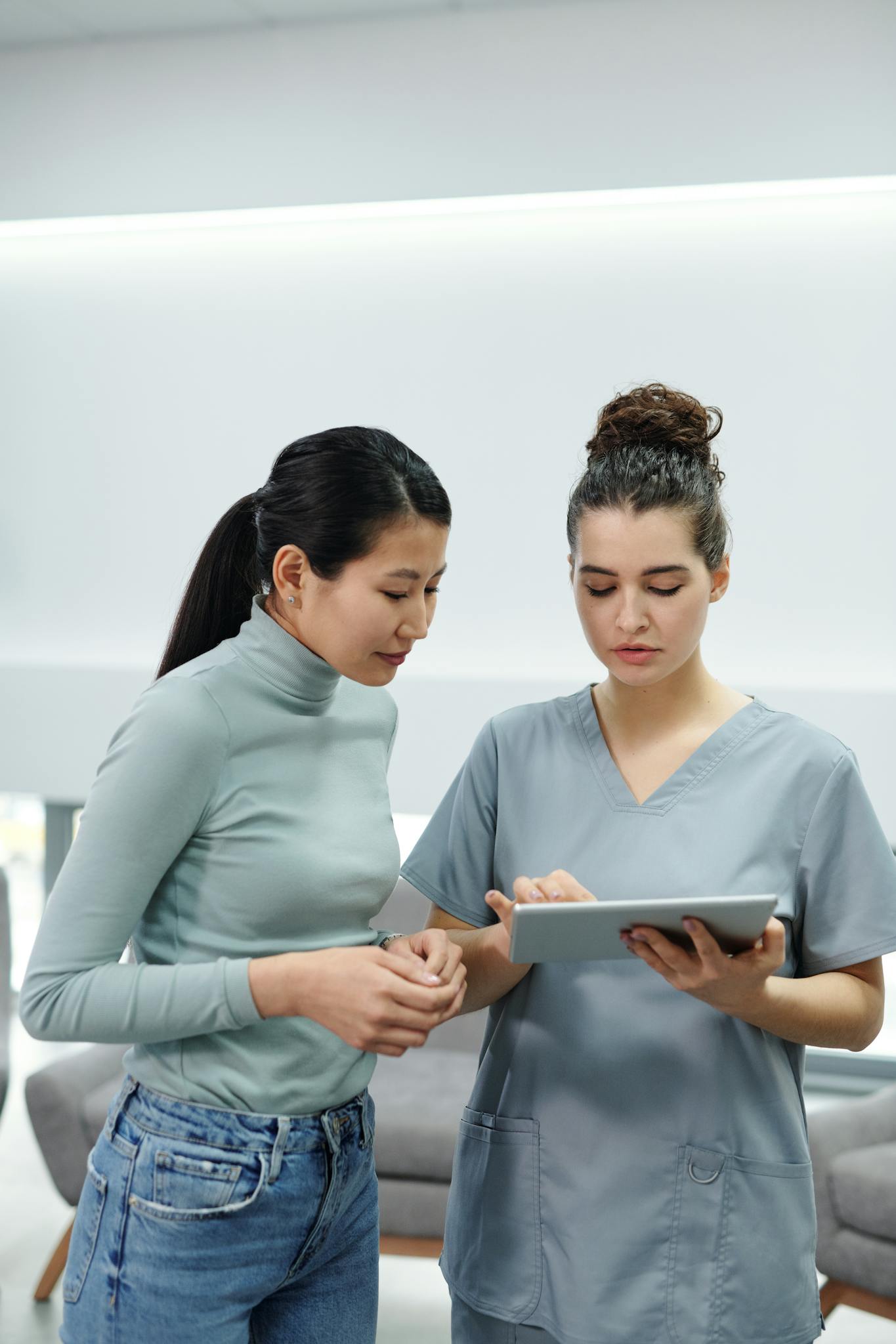 Healthcare professional using a tablet during a consultation inside a clinic.
